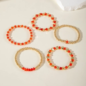 Detailansicht des fünfteiligen mehrlagigen Perlenarmband-Sets mit roten Herzen und Goldperlen