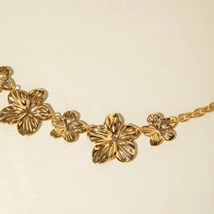 Dettaglio macro di cintura dorata con fiori 3D e texture radiali sui petali metallici