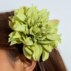 Détail d'une grande pince à cheveux pivoine en tissu vert aux bords roses sur modèle