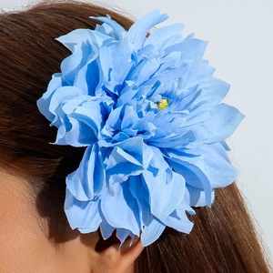 Gros plan détaillé d'une pince à cheveux pivoine en tissu bleu clair sur cheveux bruns