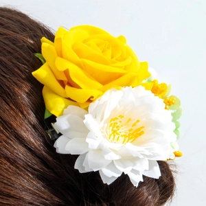 Détail de la pince à cheveux rose jaune et dahlia blanc sur cheveux bruns ondulés