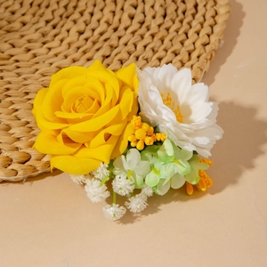 Détail de pince à cheveux avec rose jaune en soie et marguerite blanche sur tapis tressé