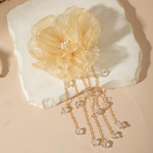 Détail de la pince pivoine en organza champagne avec pompons dorés et perles irisées