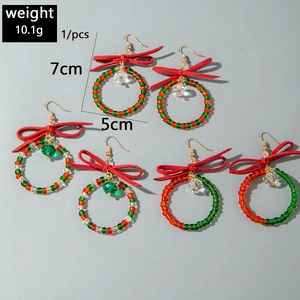 Détail de boucles d'oreilles couronne de Noël avec nœuds rouges et perles de verre