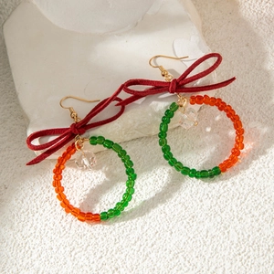 Boucles d'oreilles couronne de Noël avec nœud rouge et perles de verre sur fond de pierre