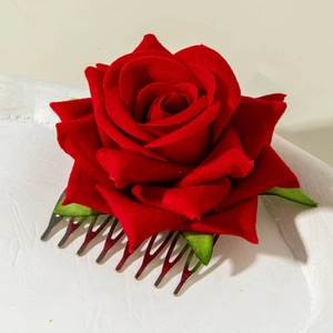 Detailed close-up of a red silk rose hair comb with green leaves and silver metal teeth
