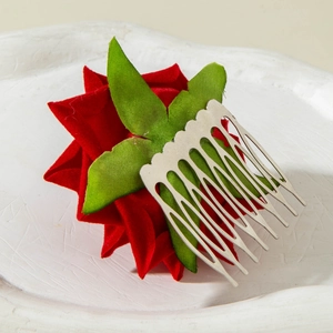 Detail of red satin rose hair comb with green fabric leaves and silver metal tines