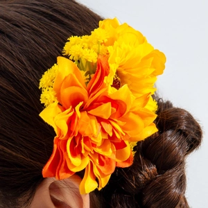 Close-up of bohemian orange and yellow silk flower hair comb on braided brown hair