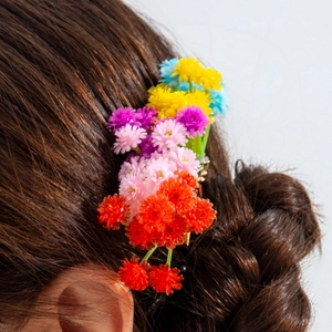 Detailed close-up of colorful floral hair comb set in a dark brown braided hairstyle