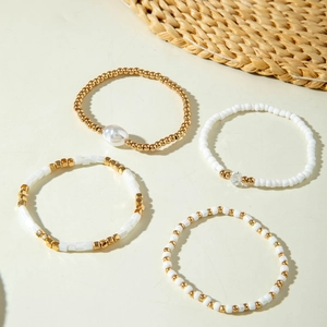 Détail d'un ensemble de quatre bracelets bohèmes avec perles dorées et nacres blanches