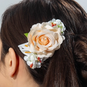 Detail of cream silk rose hair comb with small white blossoms and green leaves