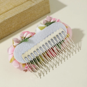 Detail view of pink fabric flower hair comb showing the silver metal teeth and back structure