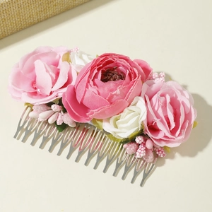 Detail of pink fabric roses and green leaves on a silver metal hair comb for weddings
