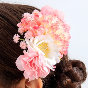 Detail of pink and white fabric flower hair comb on a brunette bun for bridal events
