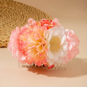 Detail of pink and white faux flower hair comb with silver tines and boho tassels