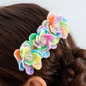 Detail of colorful resin flower hair clip with beads on a braided hairstyle