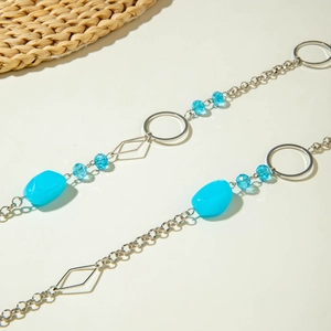Detail van een lange kralenketting met hemelsblauwe harsstenen en zilverkleurige schakels
