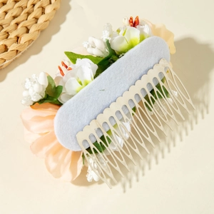 Detail of floral hair comb with realistic cream and pink flowers and silver metal teeth