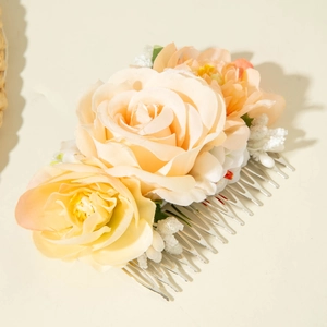 Close-up of bohemian champagne fabric roses and white bead detail on a silver hair comb