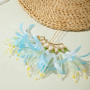 Détail de fleurs en tissu bleu et blanc sur un peigne à cheveux doré à double broche