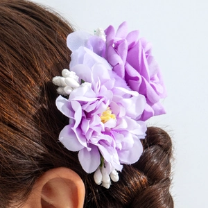 Détail d'un peigne à cheveux à fleurs violettes sur une tresse brune pour un look de vacances