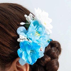 Détail d'un peigne à fleurs bleues et blanches en soie sur un chignon tressé élégant