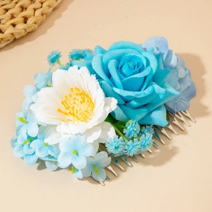 Détail de roses bleues et fleurs en tissu blanc sur un peigne à cheveux en argent