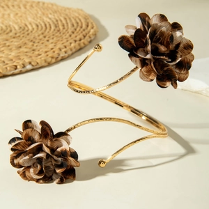 Detail eines goldenen Spiral-Armreifs mit Stoffblumen im Leopardenmuster und Hammerschlag