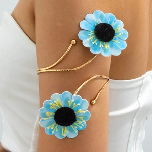 Detailaufnahme einer goldenen Oberarmspange mit blauen Stoffblumen an einem Modell