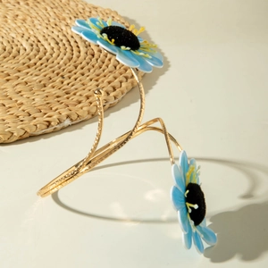 Detailaufnahme der goldenen Oberarmspange mit zwei himmelblauen Stoffblumen