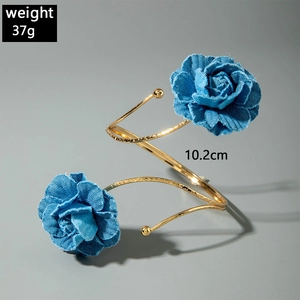 Makroaufnahme von 3D-Denim-Rosen und goldener strukturierter Spiral-Oberarmspange