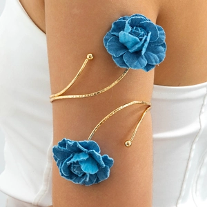 Detail eines goldenen gehämmerten Armreifs mit blauen 3D-Stoffblumen-Verzierungen