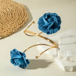 Detail eines goldenen Armreifs mit Denim-Rosenblüten und gehämmerter Metallstruktur