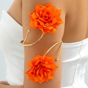 Detail eines goldenen Spiral-Armreifs mit großen orangefarbenen Stoffblumen am Arm