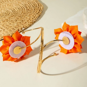 Detail von orangen Stoffblumen auf verstellbaren goldenen Armmanschetten aus Metall