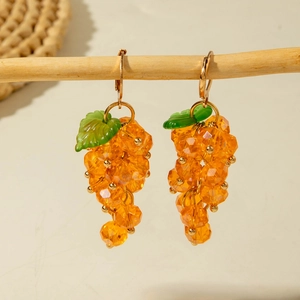 Detailed view of orange grape beaded drop earrings on a natural wood branch