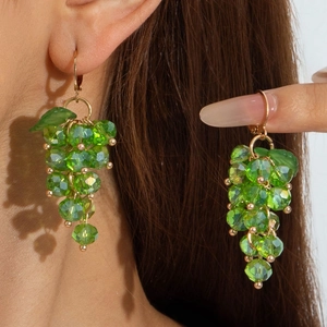 Close-up of bright green crystal grape bunch earrings with gold hooks on a model