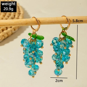 Detailed view of handmade blue grape beaded earrings featuring green leaf and gold hoop