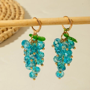 Fashionable sky blue grape bead drop earrings with green leaves on wooden display