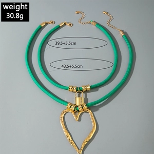 Green cord and gold layered necklace with a large textured heart pendant and lock detail