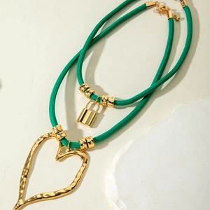 Detail of green woven cord necklaces with gold heart pendant and gold lock charm