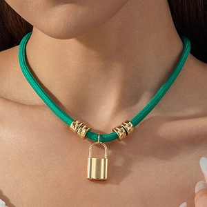 Close-up of green woven cord necklace featuring a gold metal lock pendant and ribbed beads