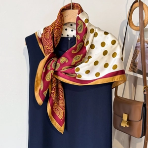 Elegant paisley and polka dot silk scarf tied on a blue dress, lifestyle flat lay
