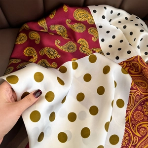 Close-up of silk-textured paisley and polka dot patchwork scarf on leather surface