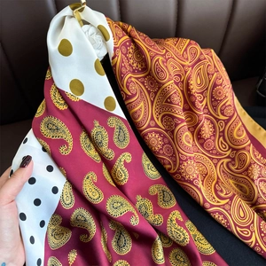 Classic paisley and polka dot patchwork silk scarf hanging on a golden hanger