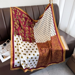 Retro silk scarf featuring paisley and polka dot patchwork on a vintage leather sofa