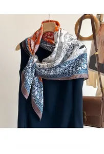 Detailed view of paisley silk-feel scarf styled on a chic navy sleeveless blouse