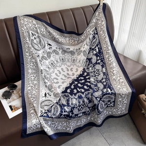 Detail of navy paisley silk scarf draped on a leather sofa with vintage accessories