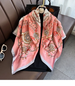 Detailed macro view of luxury chain print and satin texture on a large square neck scarf