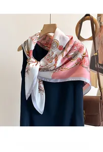 Close-up of pink silk scarf with gold chain print styled on a dress for elegant look